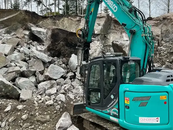 Grävmaskin i sprängd bergmassa vid markarbete i Strömstad